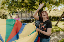 Menschen spielen mit einem bunten Tuh im Garten