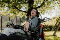 Mann sitzt im Rollstuhl und genießt den Frühling im Garten