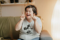 Eine Bewohnerin sitzt auf der Couch und treibt ihre Späßchen