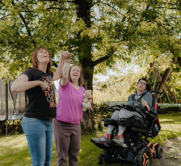 Drei Bewohner:innen erholen sich im Garten der Wohngemeinschaft von Noh Bieneen