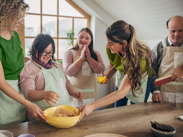 Eine Gruppe von Menschen backen gemeinsam und haben Spaß