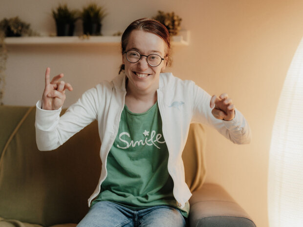 Bewohnerin des Wohnhauses bei Noh Bieneen sitzt lachend auf dem Sofa